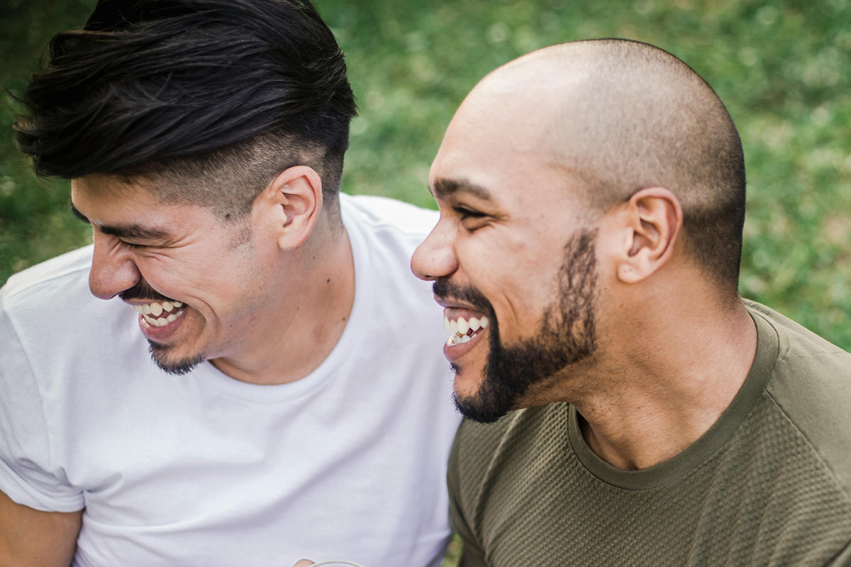 Two men laughing wholeheartedly, sharing a joyful moment that lifts their spirits and relieves stress.