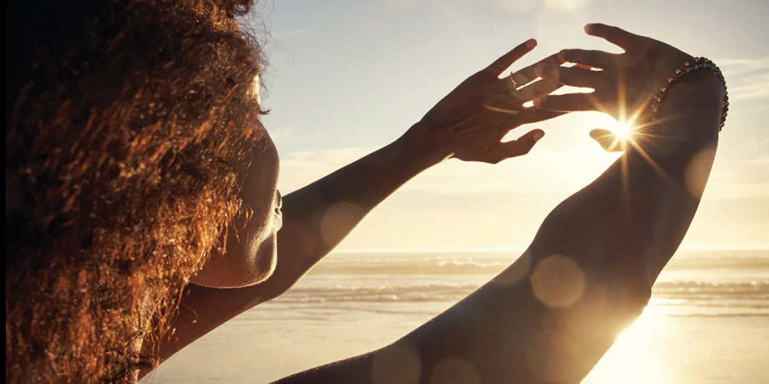 A woman shielding her eyes from the sun with her hands at the beach, enjoying the natural surroundings.